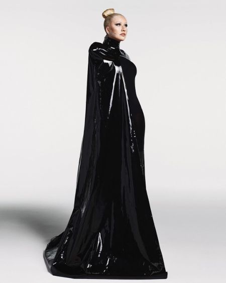 Christina Aguilera in a black dress poses for a photoshoot.